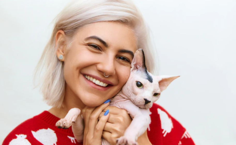 smiling woman hugging a sphinx cat with no fur